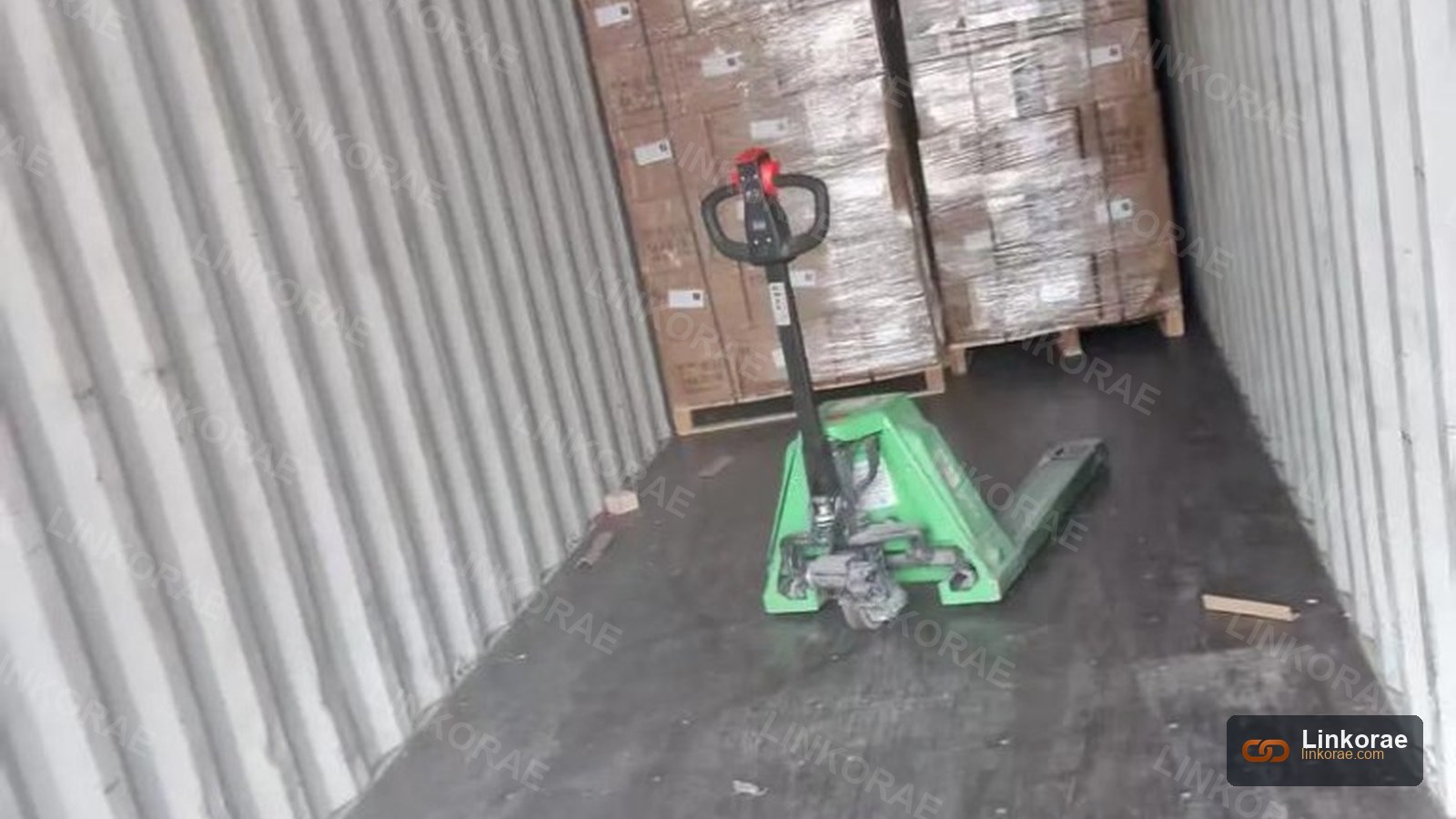 A pallet jack inside a container facing stretch-wrapped cargo — classification is already set
