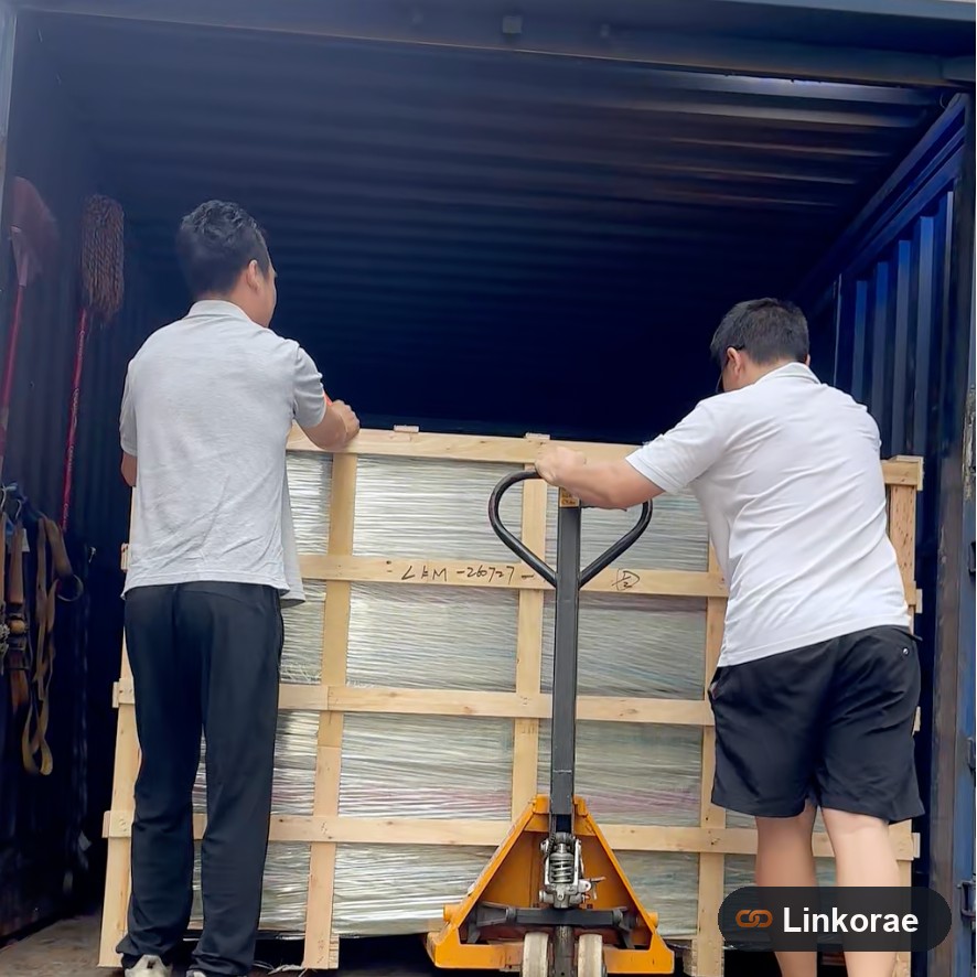 Crew rolling a wooden crate into a container at origin — handling that a thin quote often skips